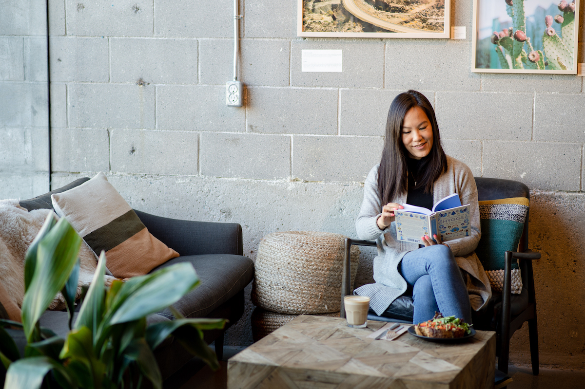 Girl Reading The Little Book of Hygge: Danish Secrets to Happy Living at a cafe